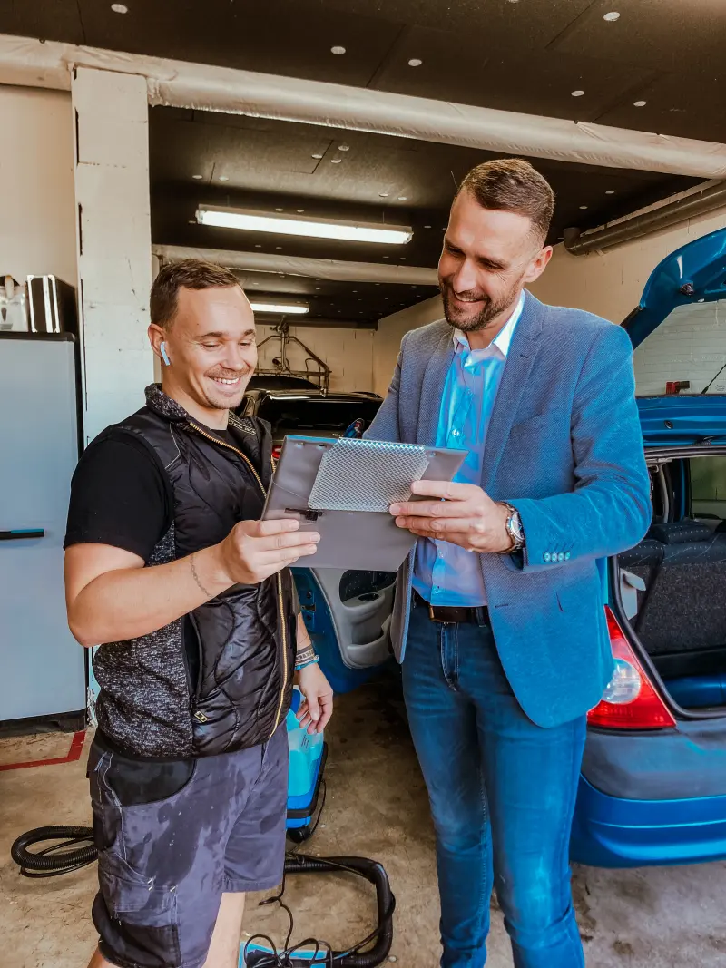 Un mécanicien et un conseiller d'EC Automobiles regardent une tablette dans l'atelier