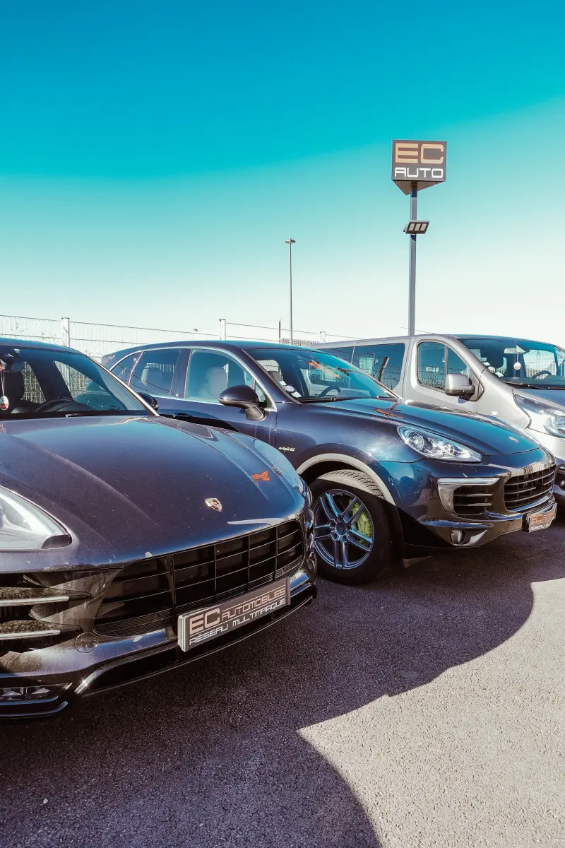 Porsche et BMW alignées sur le parc sous un ciel bleu